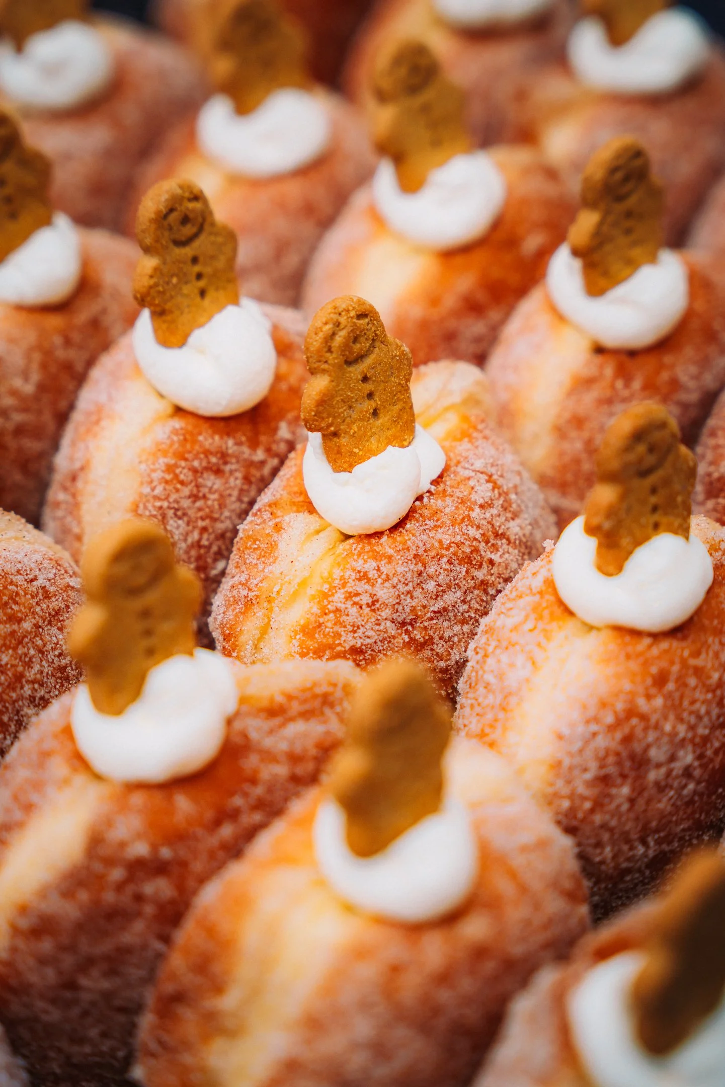 A display of delicious filled doughnuts, topped with a naughty dollop of cream and a cheeky mini gingerbread man. And he is really cheeky, he's smiling and everything!