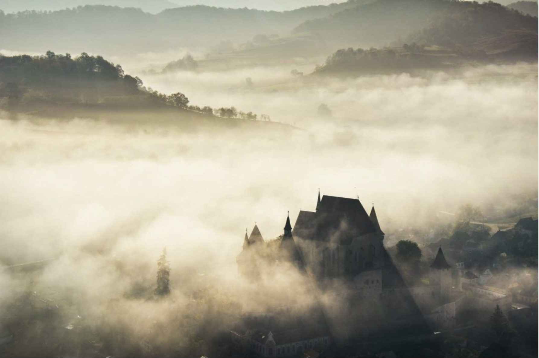 Foggy dusk over a Transylvanian castle and surrounding hills