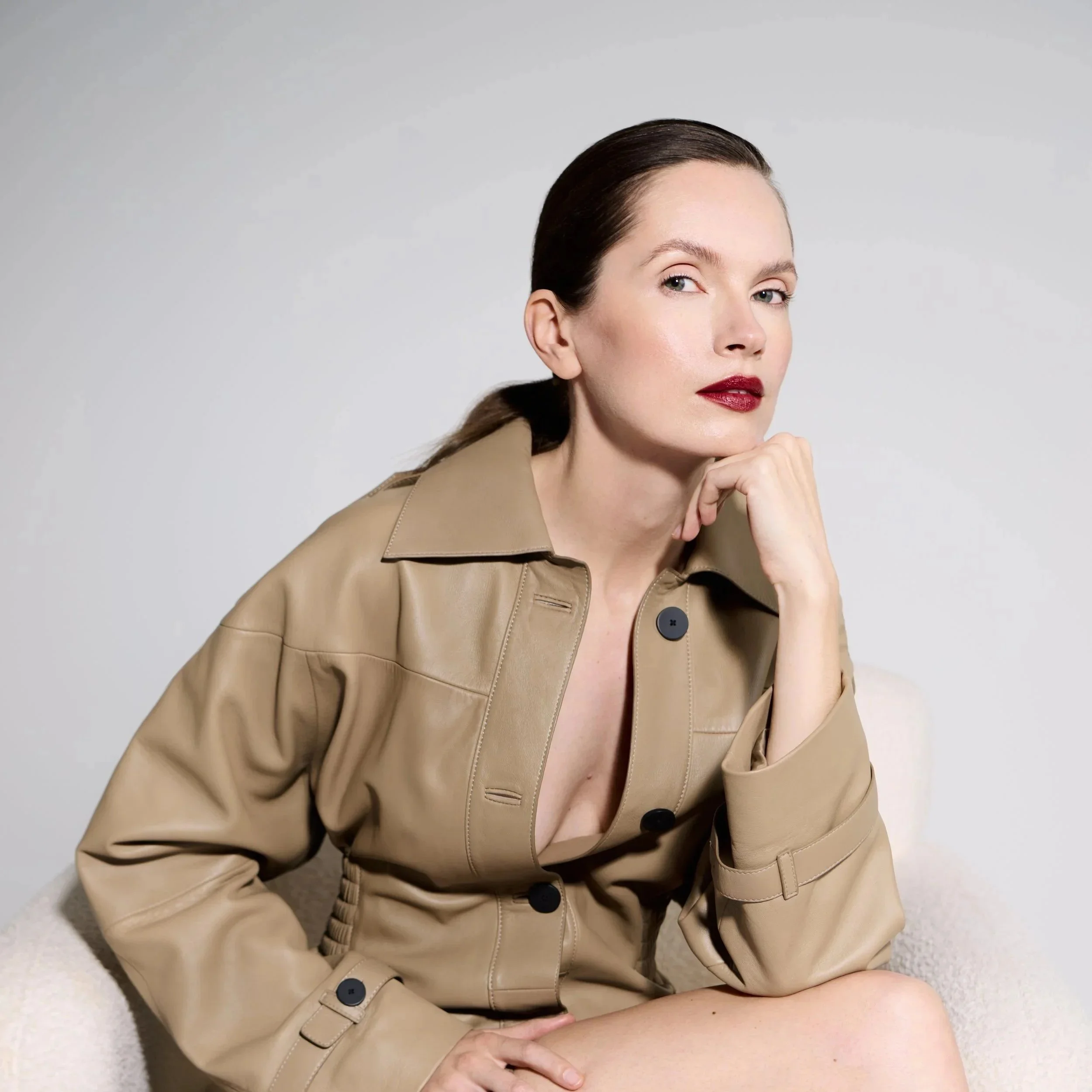 Confident woman in brown leather trench coat and red lipstick