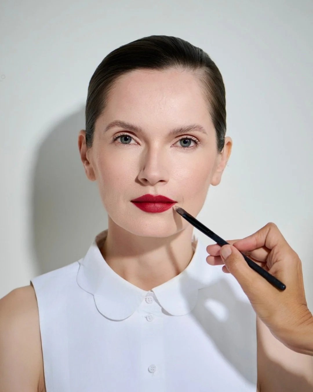 Red lipstick , and perfect modern makeup beeing applied to a beutiful model by Anna Nenoiu Celebrity makeup artist