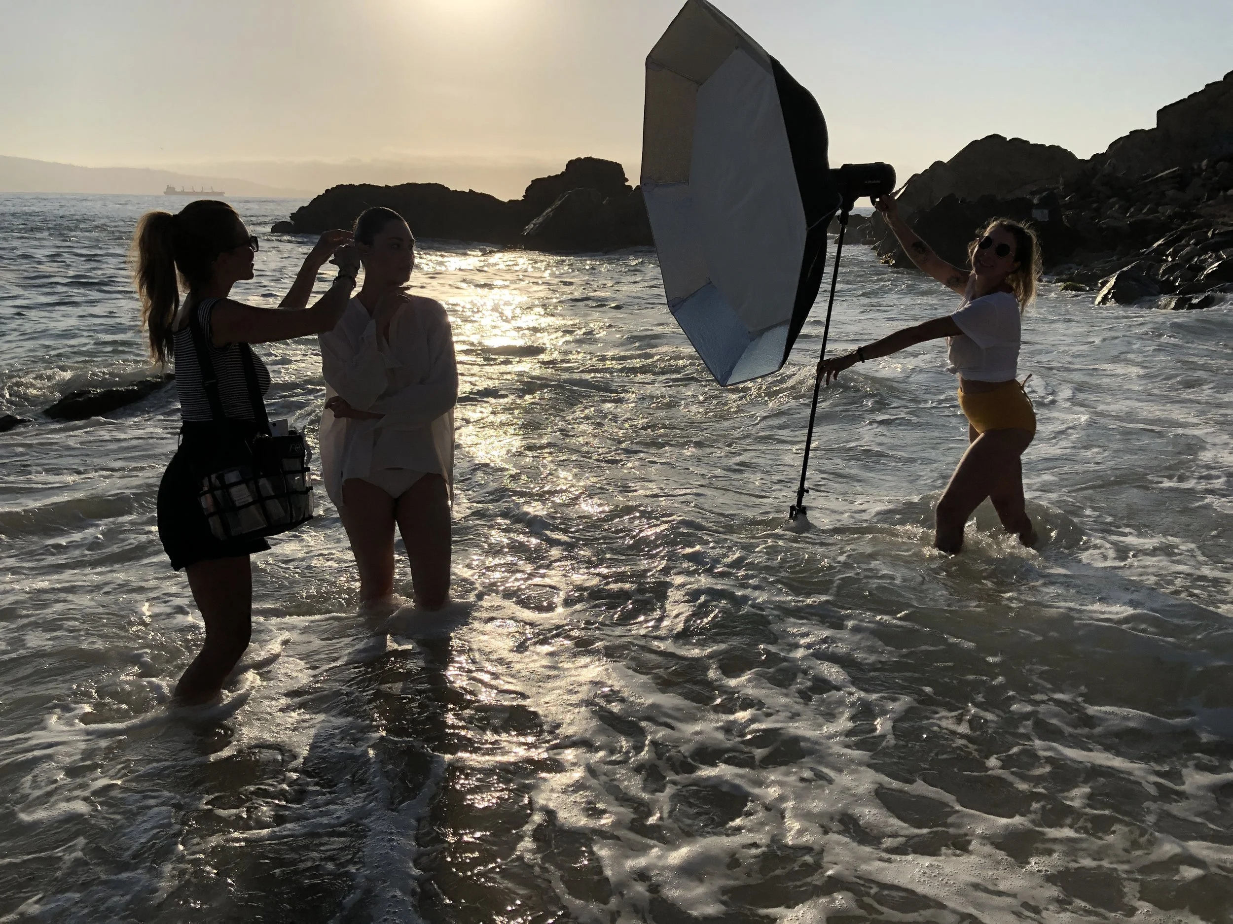 Anna Nenoiu doing hair and makeup for a model on location at a beachside photoshoot