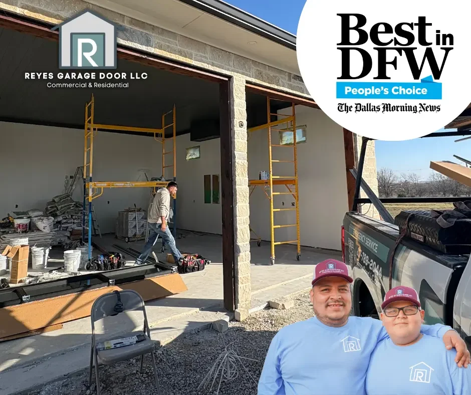 Two men wearing light blue shirts and maroon hats posing together in front of a house under construction, with scaffolding inside and a work truck nearby, during daytime.