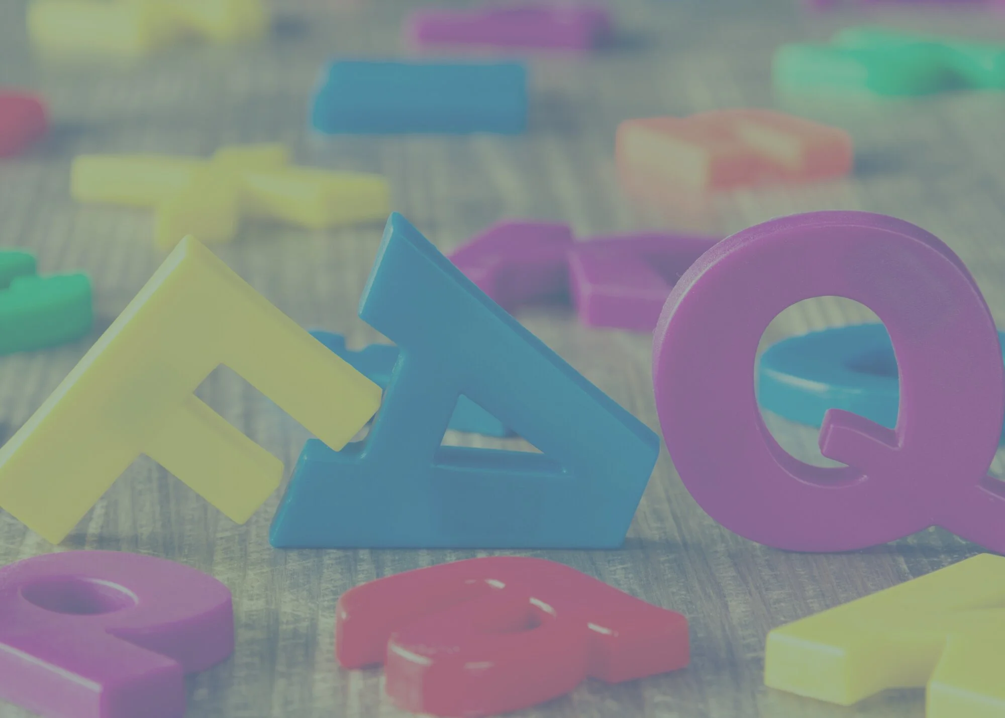 Colorful plastic letter magnets scattered on a wooden surface.