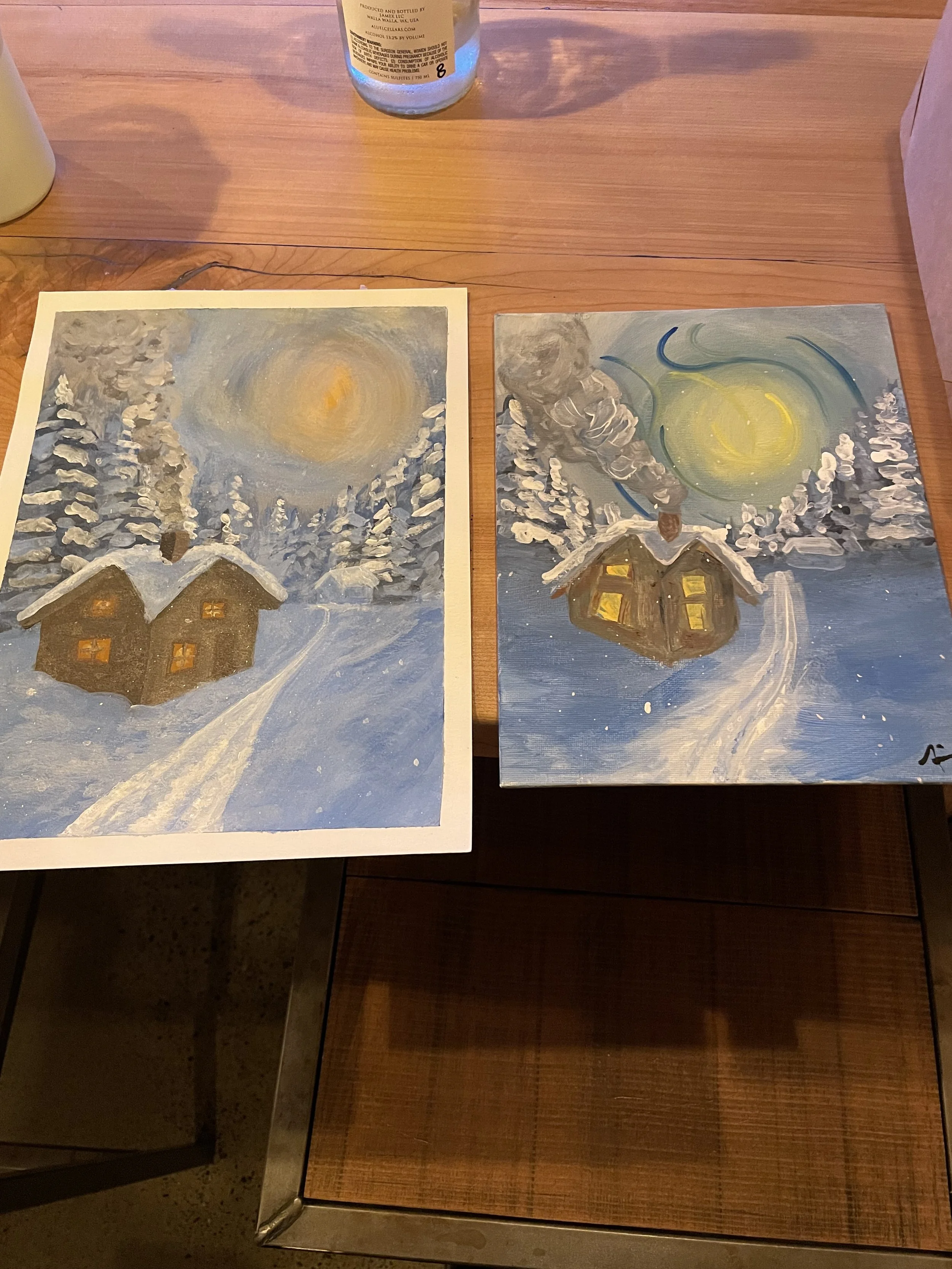 Two paintings of a winter scene with a house, snow, trees, and a bright moon or sun in the sky, with smoke coming out of the chimney.