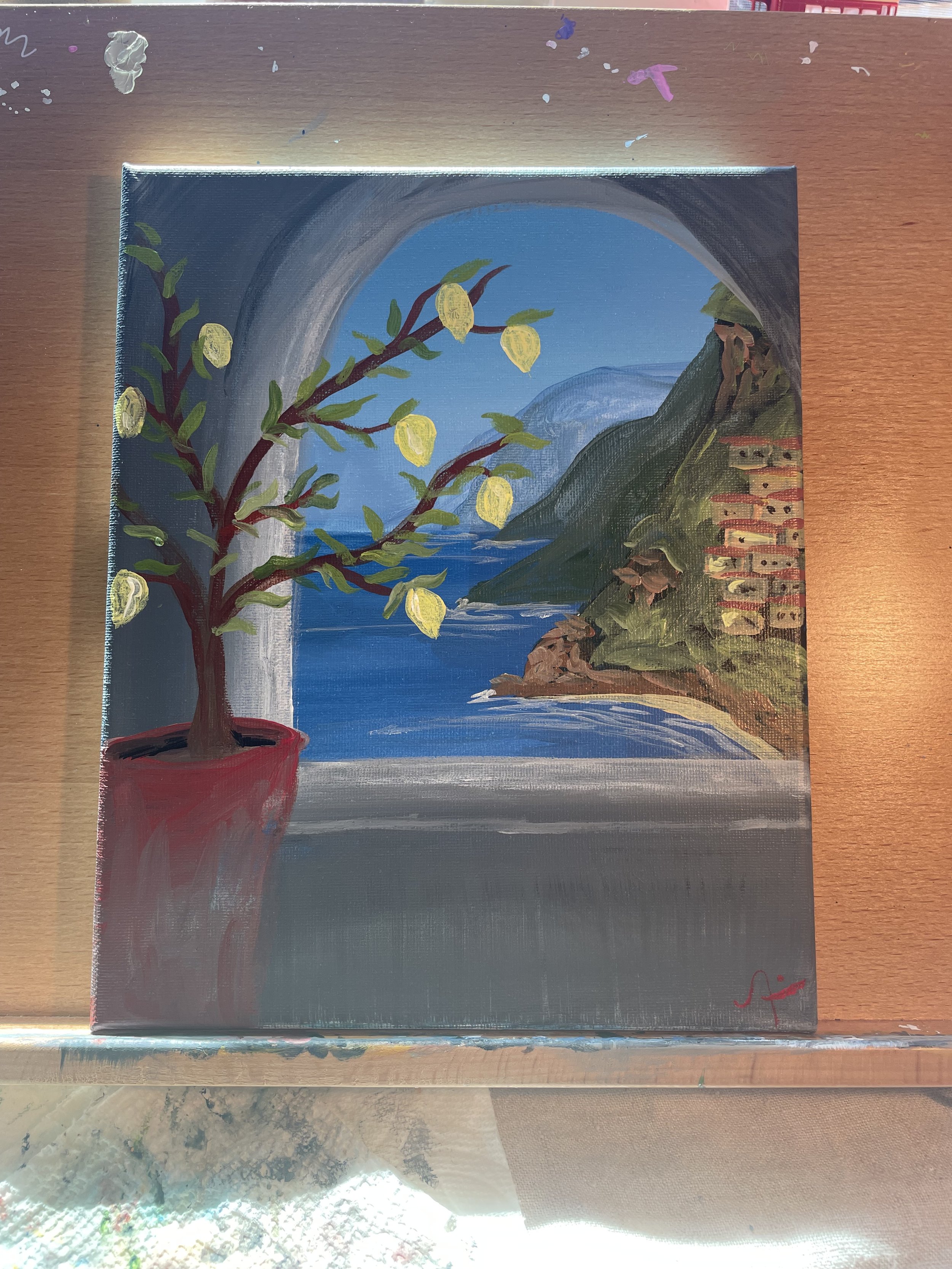 A painting of a coastal landscape seen through a window with an arched opening, featuring a lemon tree in a red pot in the foreground, blue water and mountains in the background, and a multi-story building on a hillside.