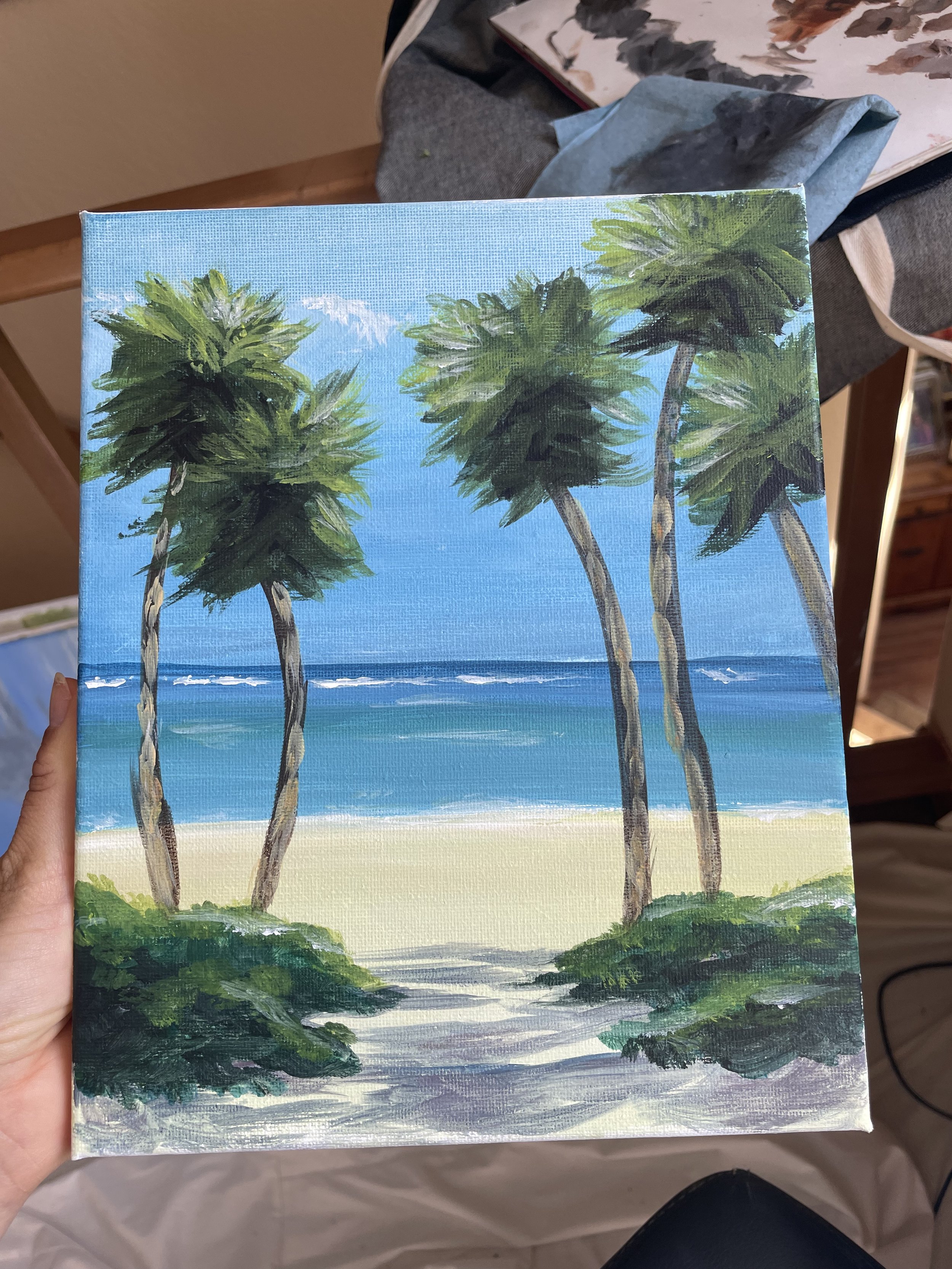 Painting of a beach scene with five palm trees, sand, ocean, and sky.