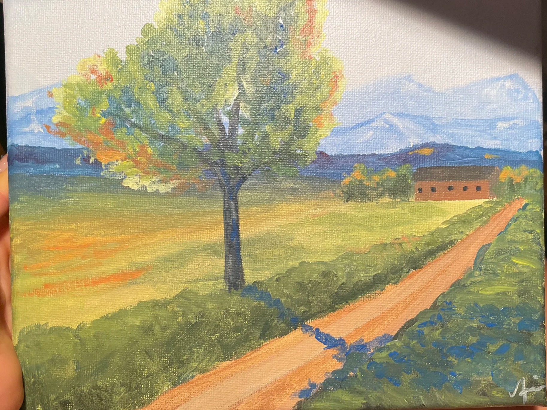 A landscape painting of a rural scene with a large tree, a dirt path, grassy fields, a small brick building, and mountains in the background, painted with vibrant colors.