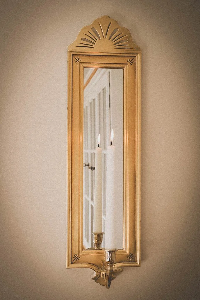 Spegellampett "Aurora", förgyller rummet med ljus som återspeglas i glaset och ger värme och ljus till inredningen. Tillverkad i svenskt lindträ förgylld med slagmetall