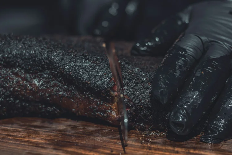 Slicing the dark bark of a smoked Cali Porker brisket