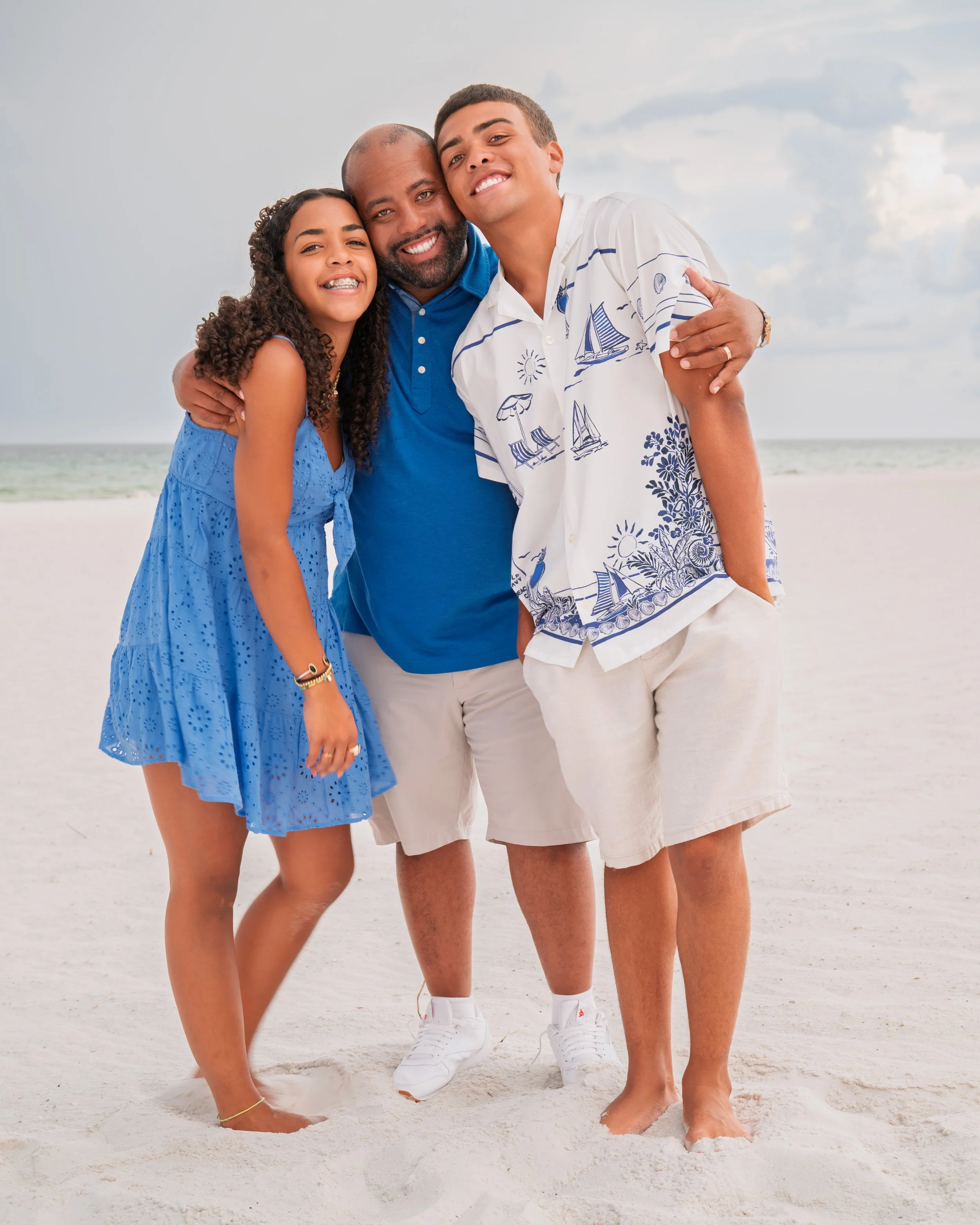 A father embraces his children on the beach for family pictures. 