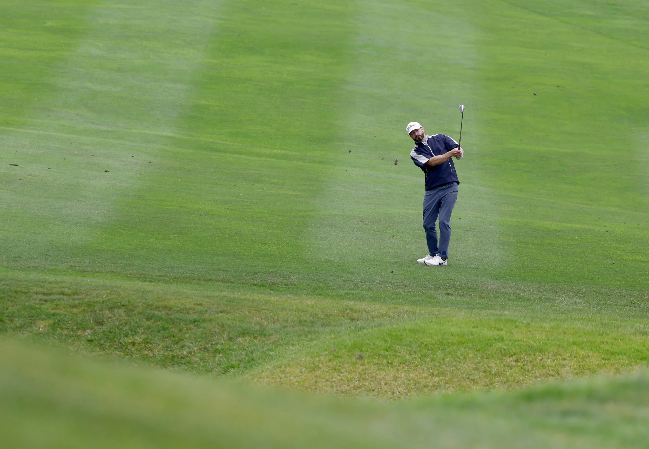 A golfer hits the ball from the fairway at Pebble Beach Golf Links
