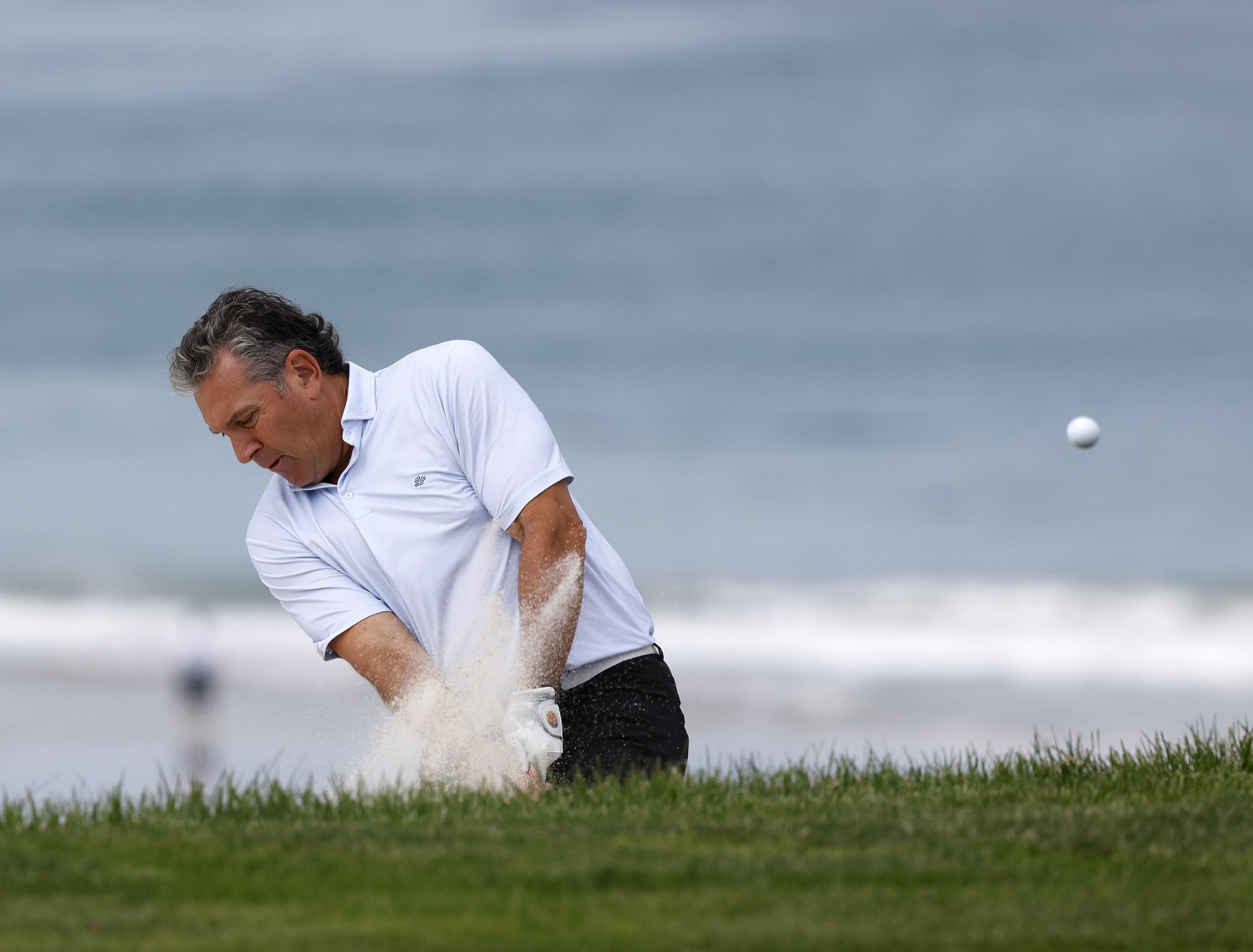 A golfer hits the ball out of a sand trap on the 7th hole at Pebble Beach Golf Links