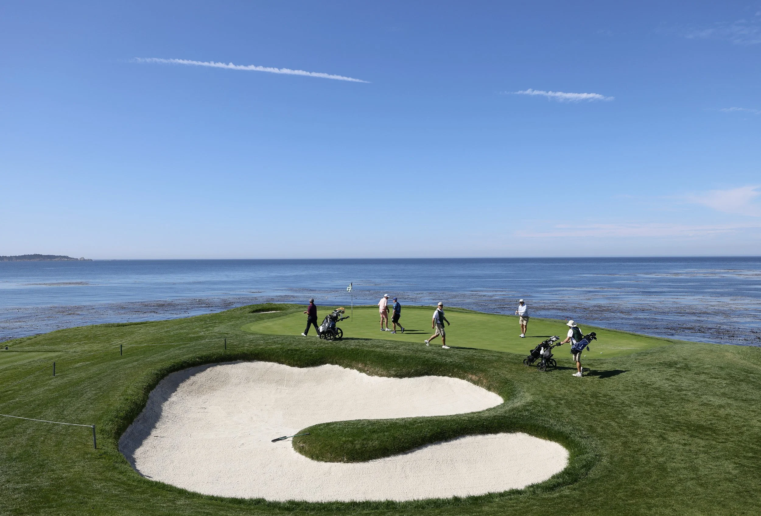 A view of the famouse hole 7 at Pebble Beach Golf Links, with green grass and blue skies