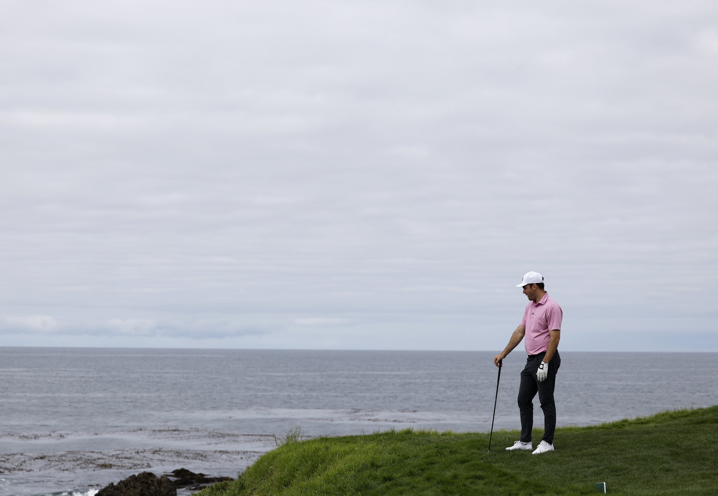 A golfer looks over the cliff on the 8th hole at Pebble Beach Golf Links