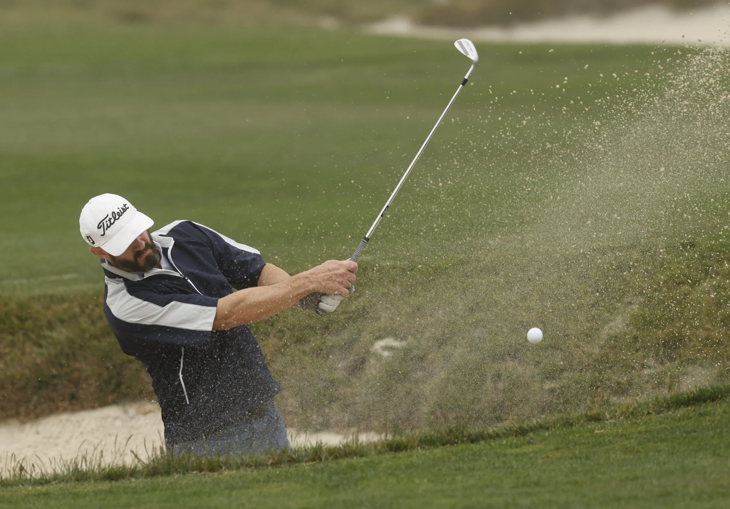 A golfer hits the ball out of the sand trap at Pebble Beach Golf Links