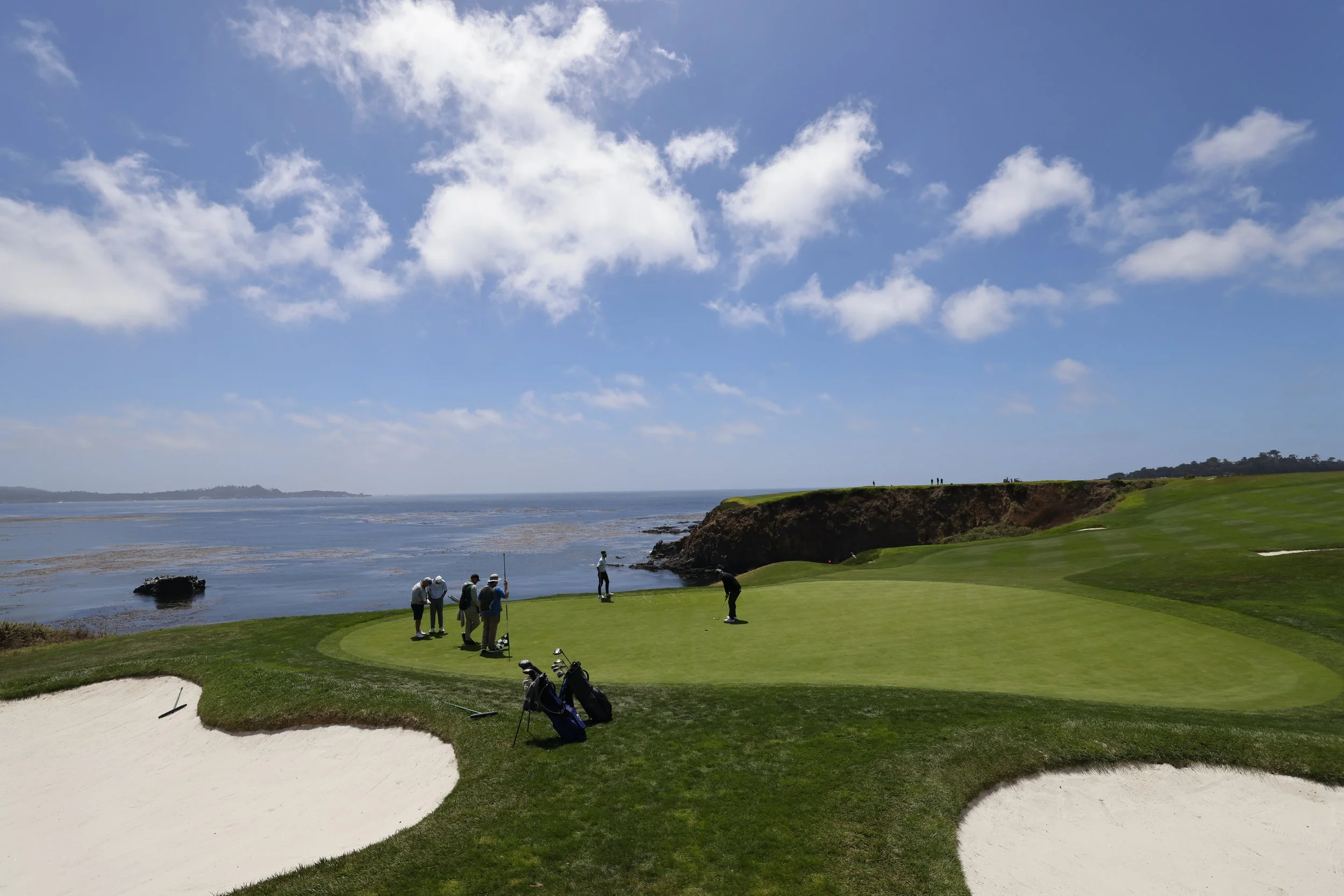 Golfers playing golf at Pebble Beach Golf Links with a beautiful blue sky