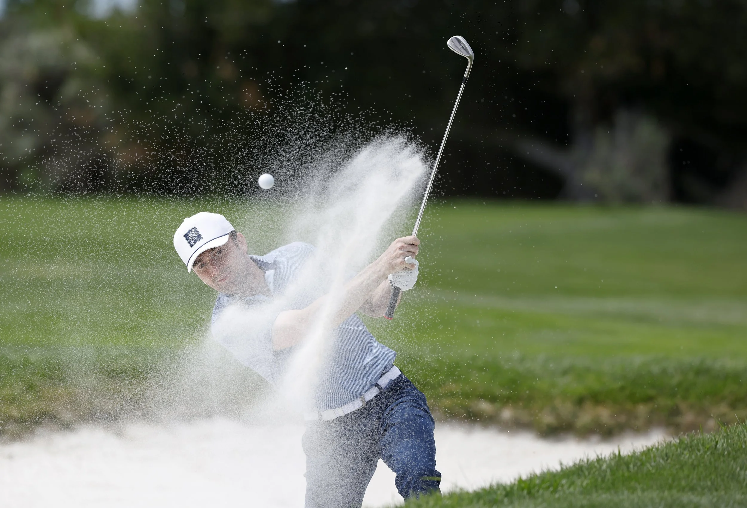 A golfer hits the ball out of the sand trap on the 3rd hole at Pebble Beach Golf Links.