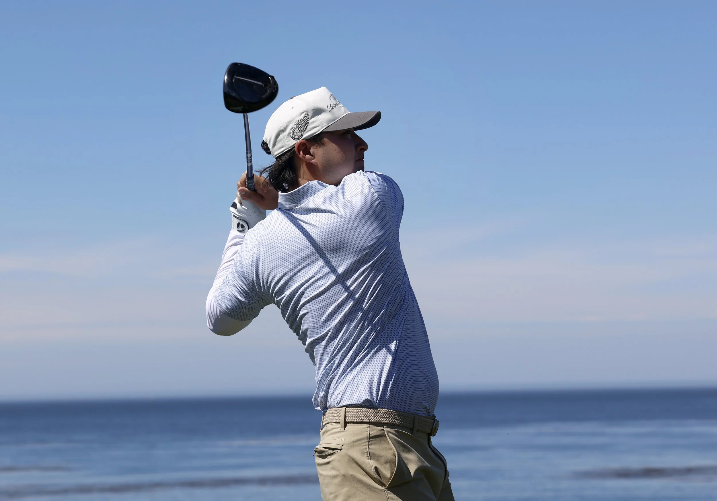 A golfer wearing a blue shirt tees off on the 8th hole at Pebble Beach Golf Links