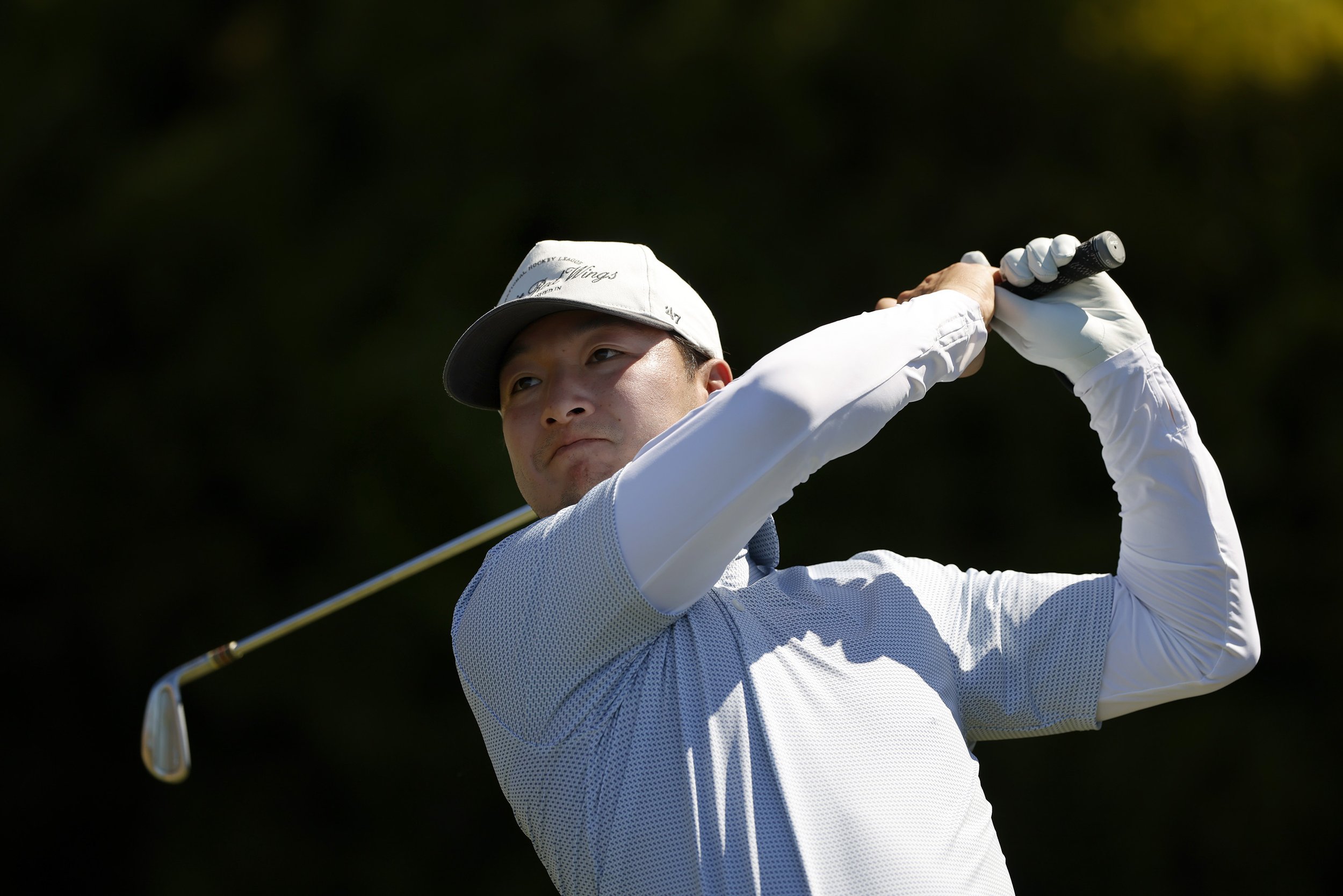 A golfer in a blue shirt and white hits the ball at Pebble Beach golf Links