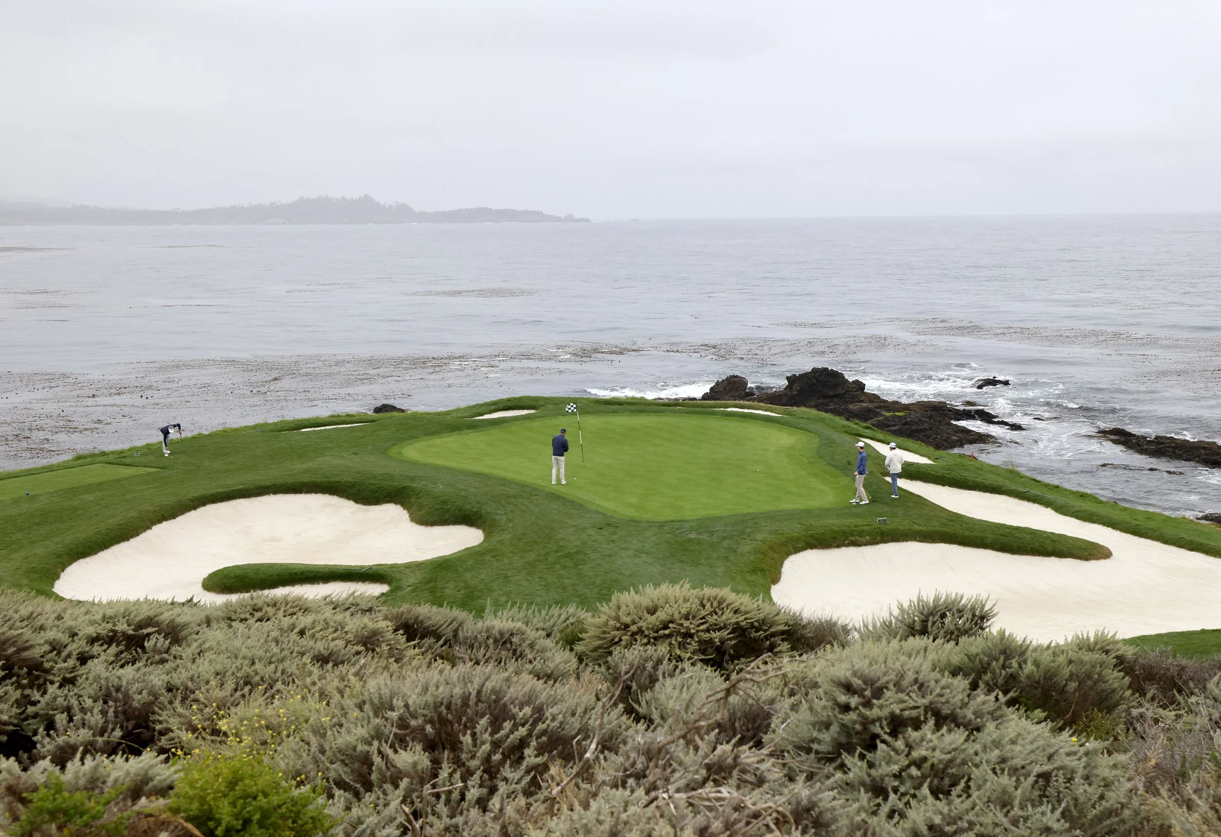 Golfers play the iconic 7th hole at Pebble Beach Golf Links