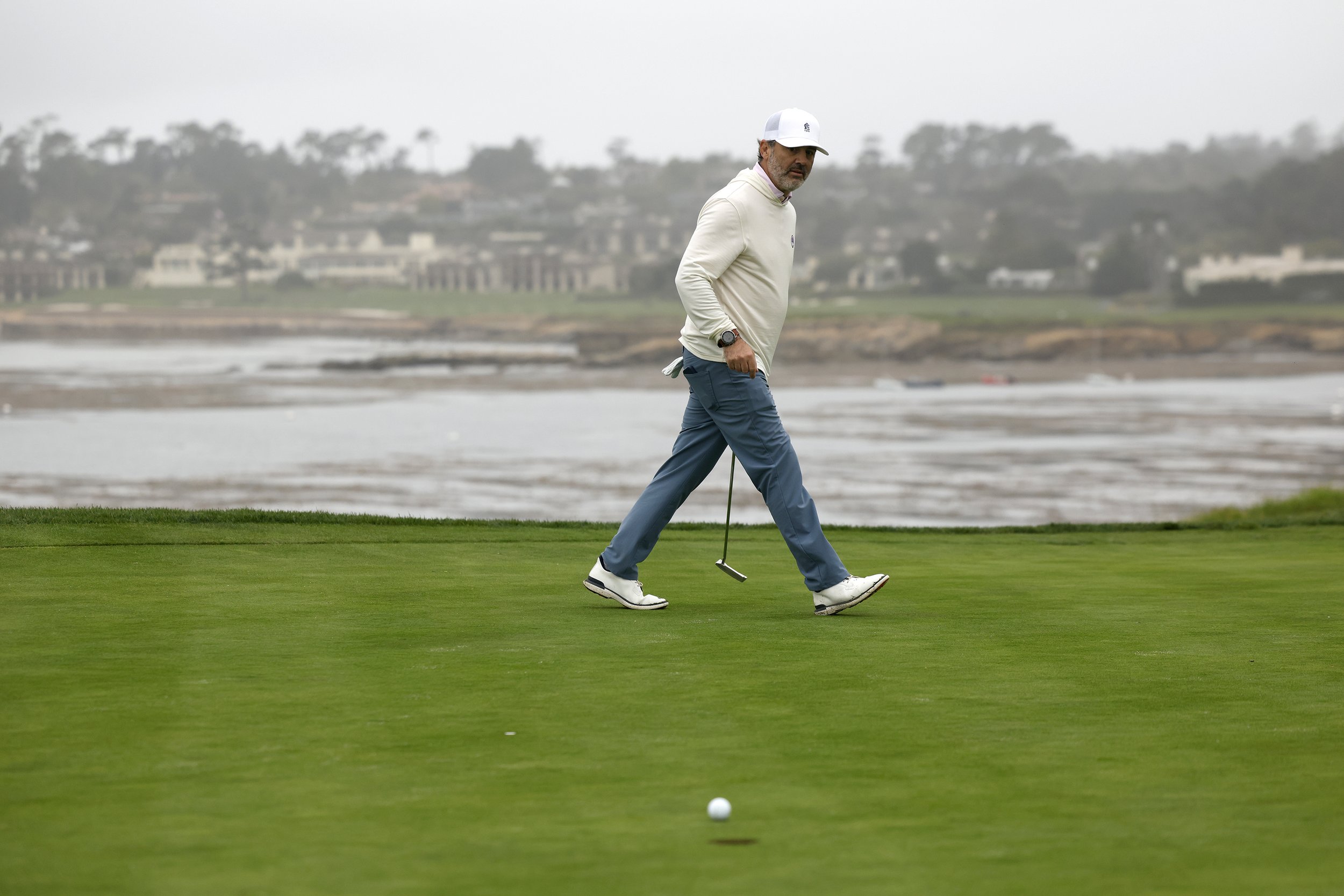 A glfer watches his ball after a putt on the green at Pebble Beach Golf Links