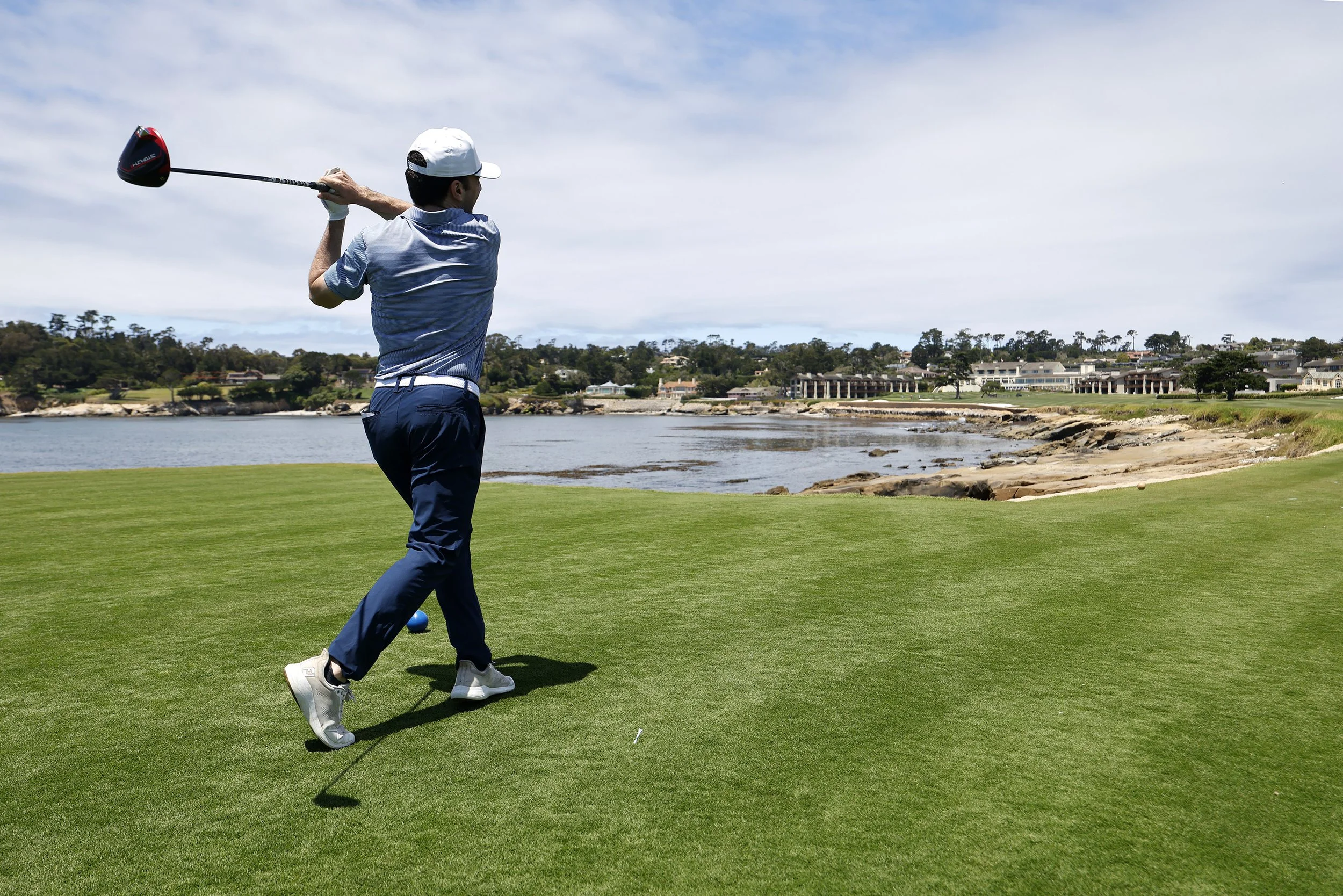 A golfer tees off on the iconic 18th hole at Pebble Beach golf Links