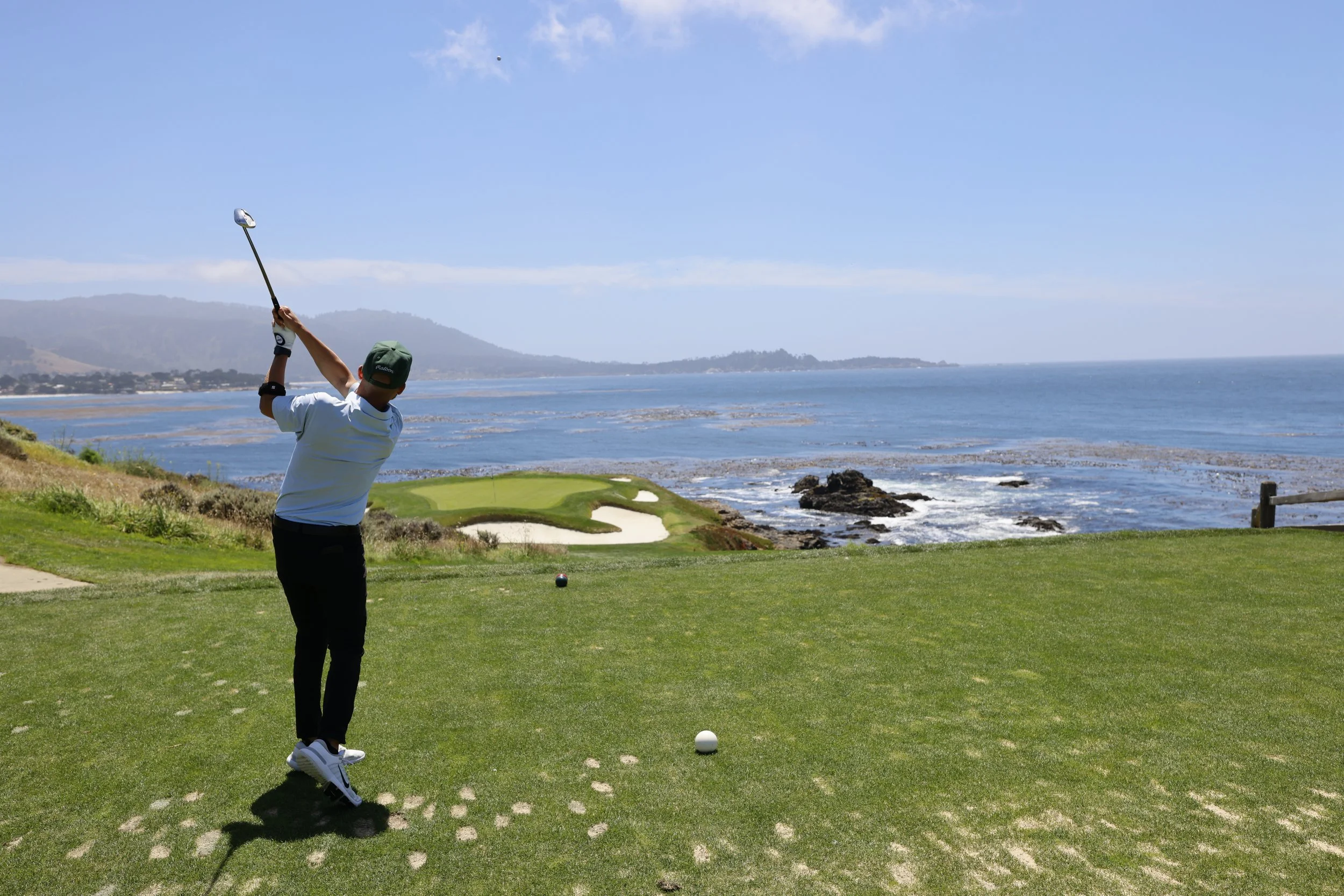 A golfer tees off on the world famous 7 hole at Pebble Beach Golf Links