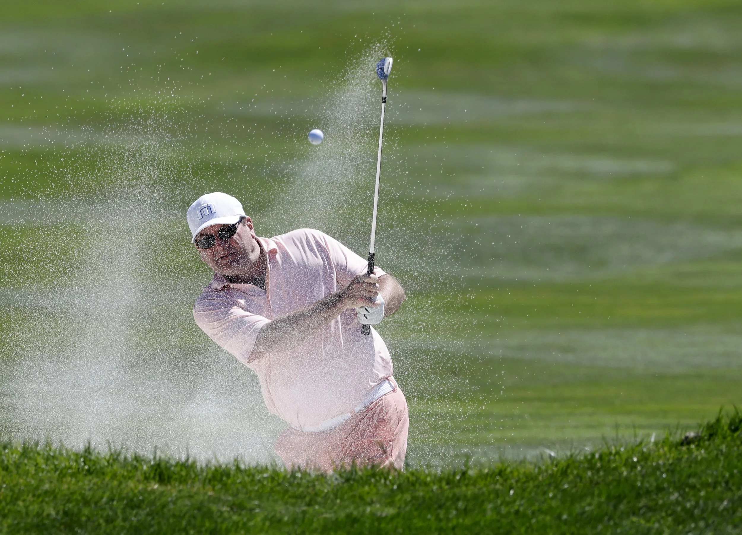 A golfer hits the ball out of a sand trap at Pebble BEach Golf Links