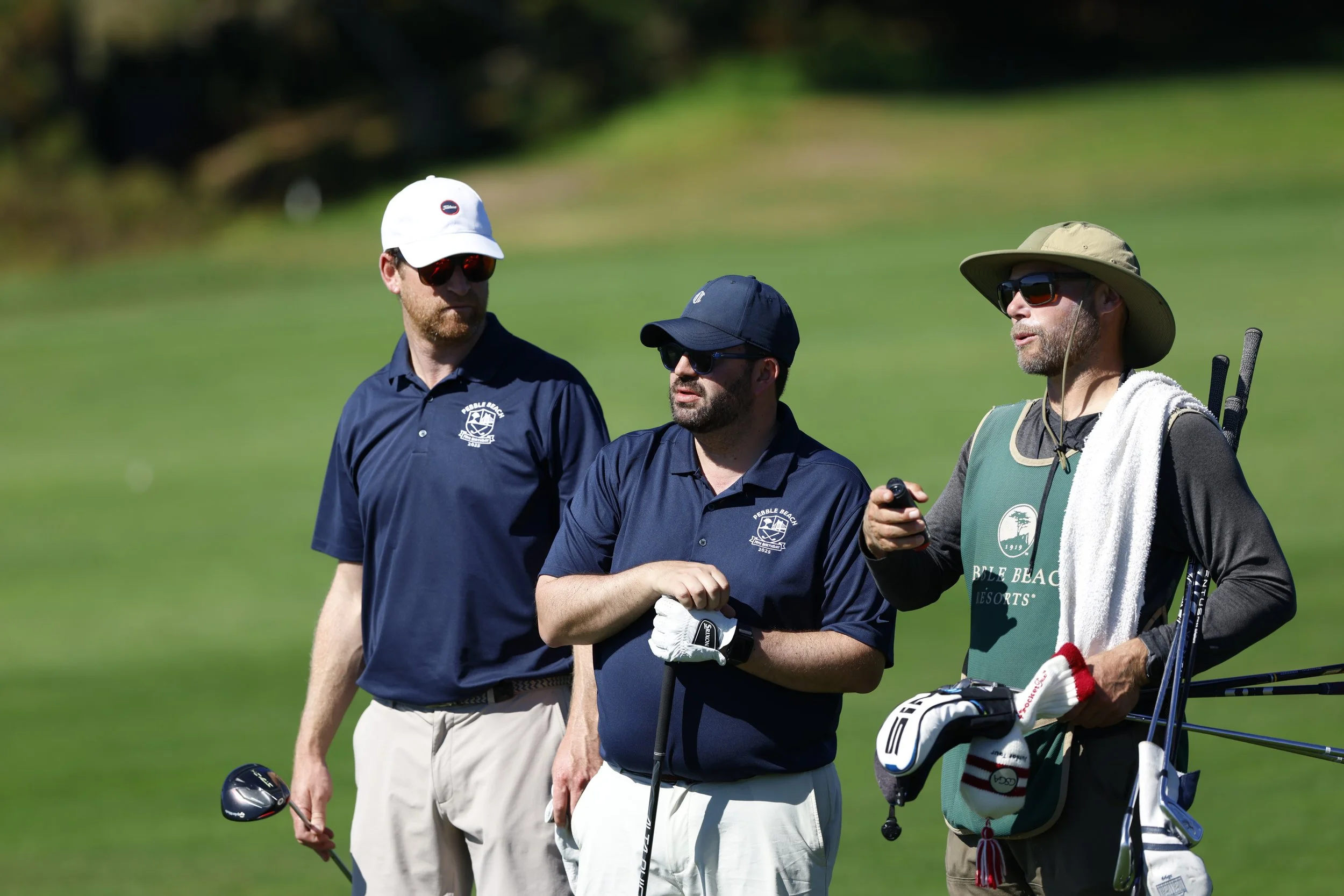 Golfers and a caddie talk during a round of golf at Pebble Beach Golf Links