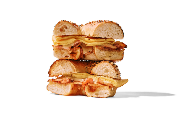 Close-up of a double cheeseburger cut in half, showing bread, slices of cheese, and bacon.