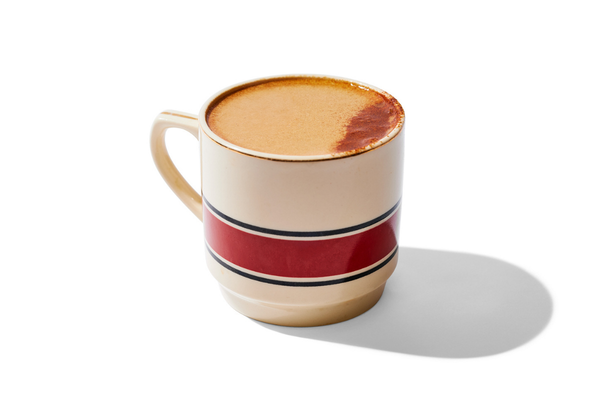 A ceramic mug filled with coffee or latte, with a decorative red and black stripe and a shadow cast on a white background.
