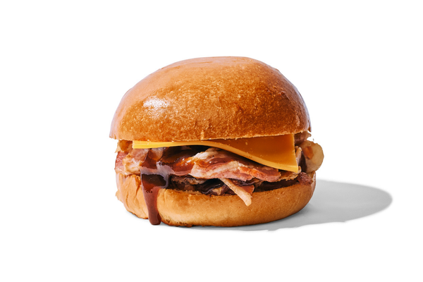 Breakfast sandwich with bacon, cheese, and a sauce or jam on a bun