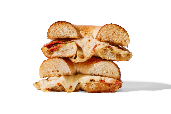 A half-eaten sandwich with melted cheese, lobster, and toasted bread slices