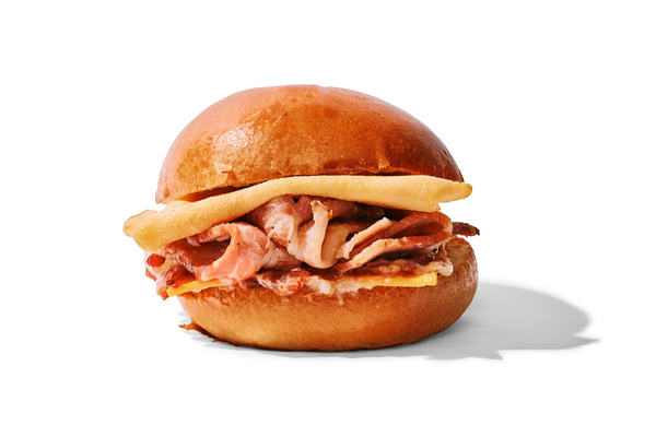 Pork roast sandwich on a bun with a slice of cheese and a fried egg