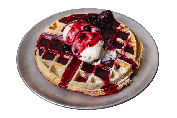 Waffle topped with vanilla ice cream, berry compote, and berry syrup on a gray plate.