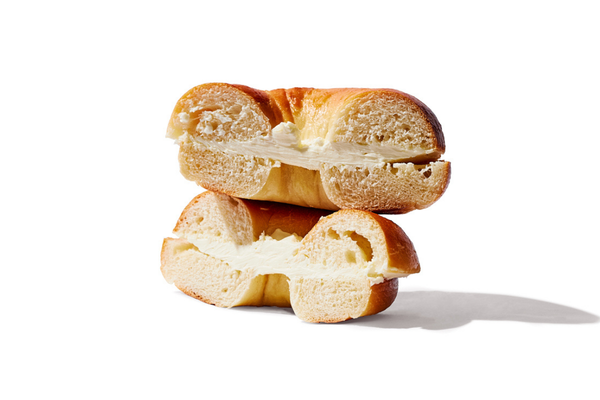 Two halves of a bread roll filled with butter, stacked on top of each other on a white surface.