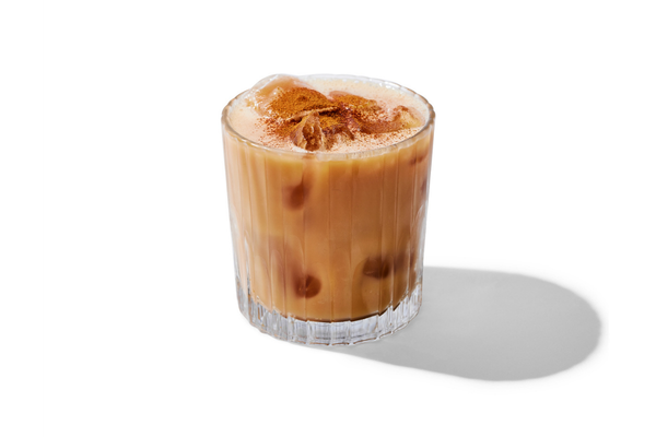 A glass of iced coffee with milk and ice cubes, on a white background.
