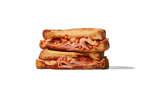 Close-up of a ham and turkey sandwich on toasted bread with a white background.