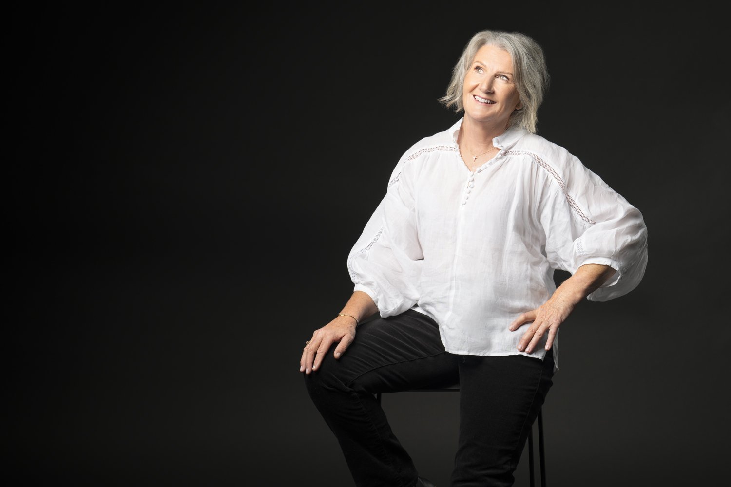 Diane Armstrong in a white shirt against a dark backdrop
