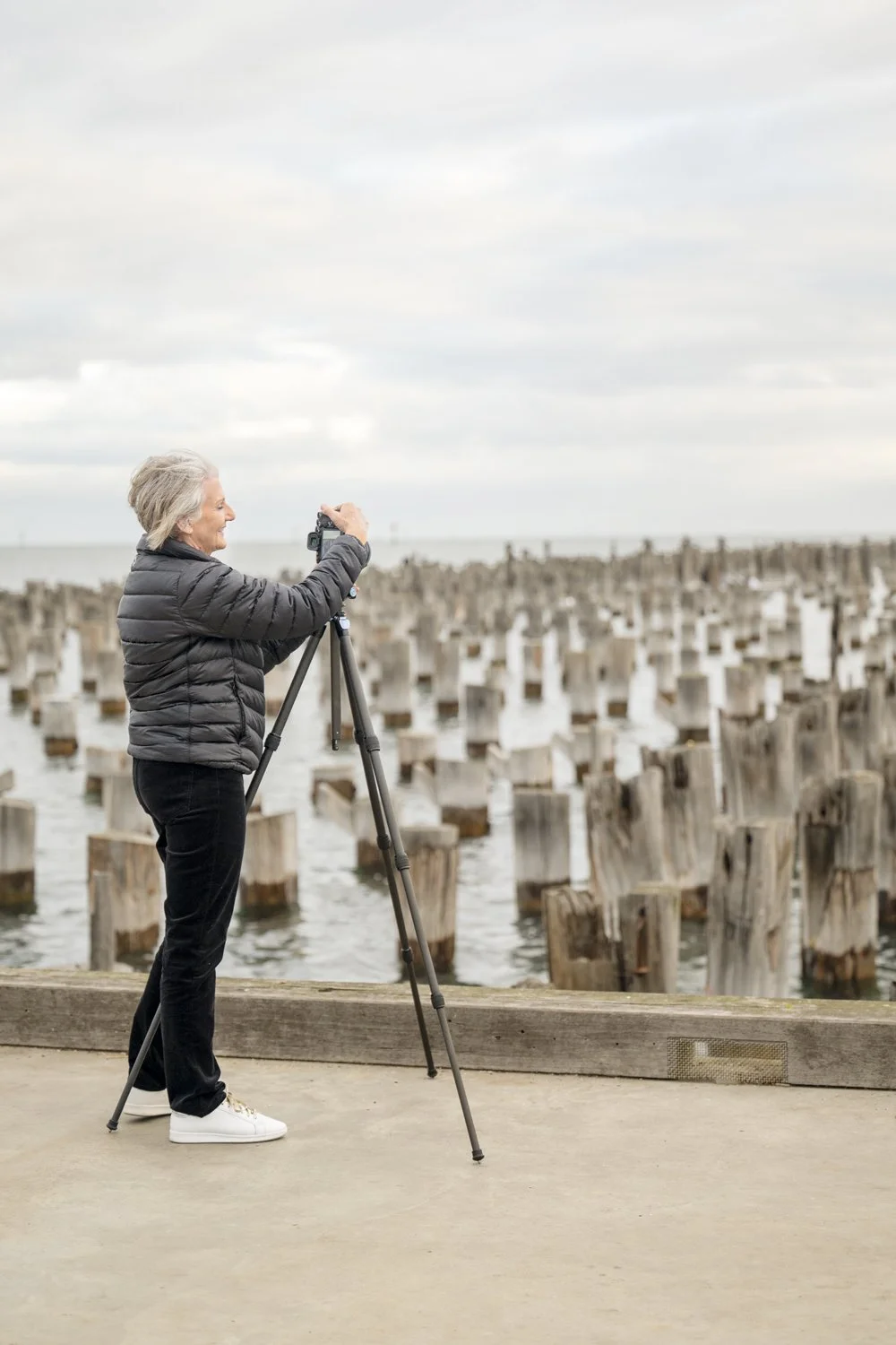 Diane Armstrong photographing old pier pylons with her camera on a tripod