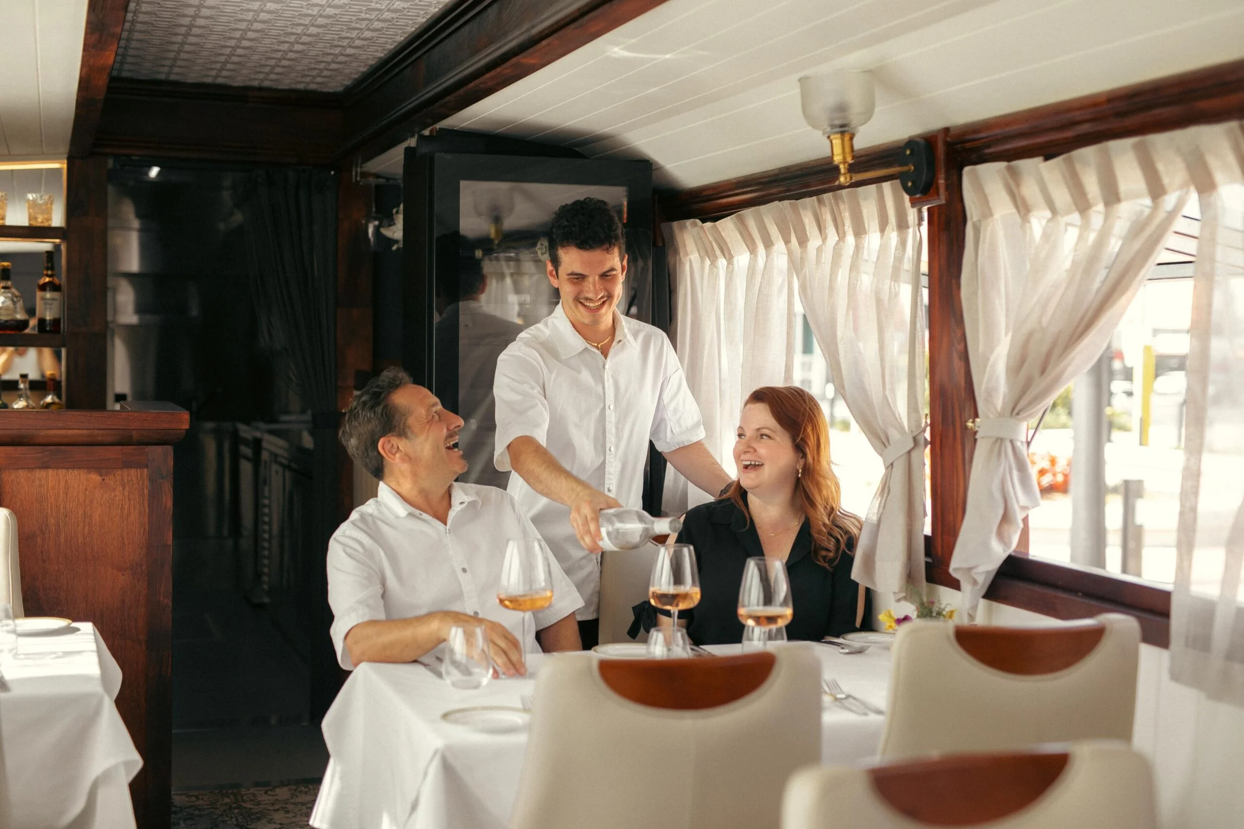 An image of Joseph, Biagio, and Sarah Biuso pouring wine on the Da Biuso bus.