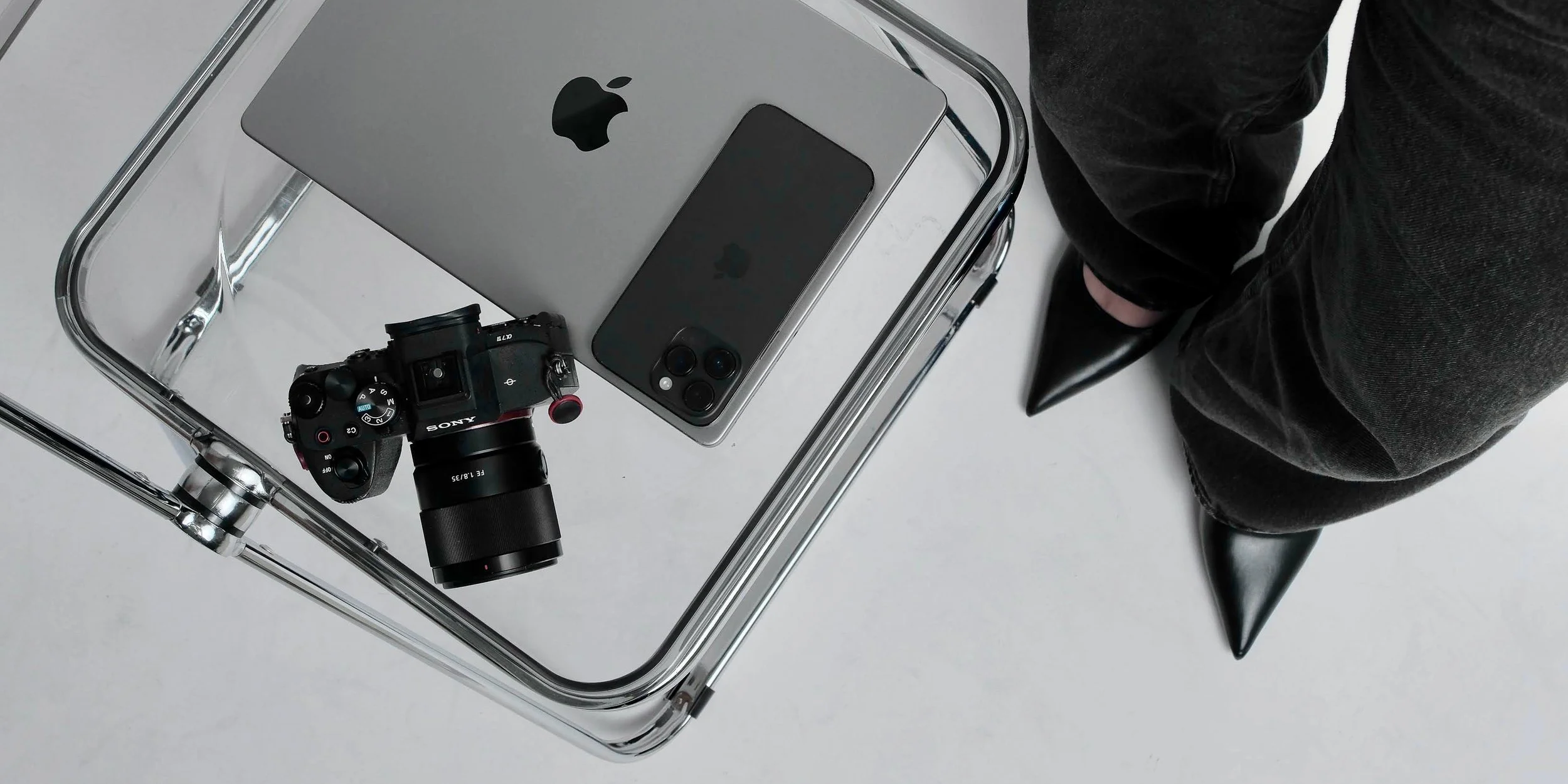An image of a camera, laptop, and phone on top a table.
