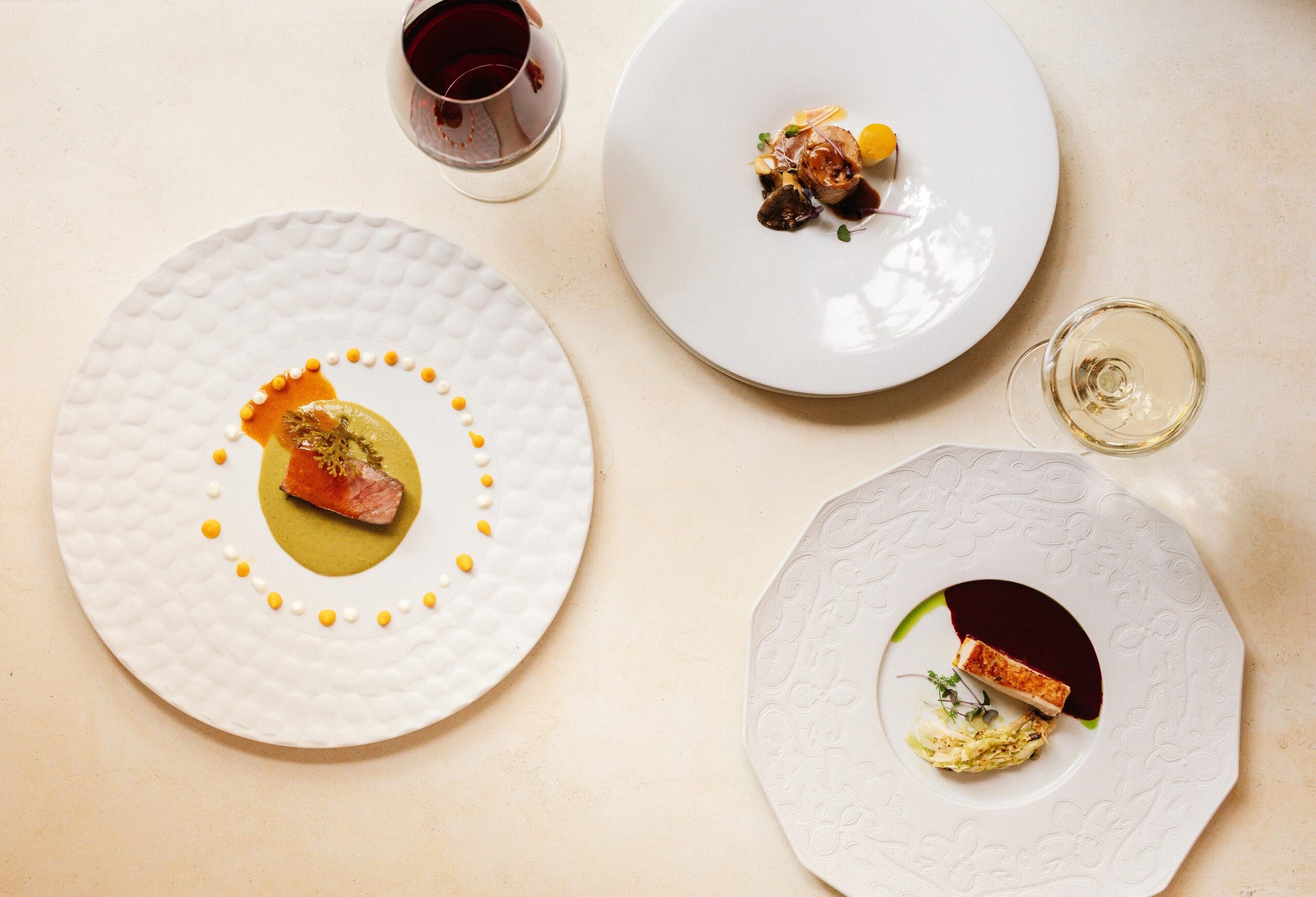 A spread of 3 highly styled dishes from birds eye view.