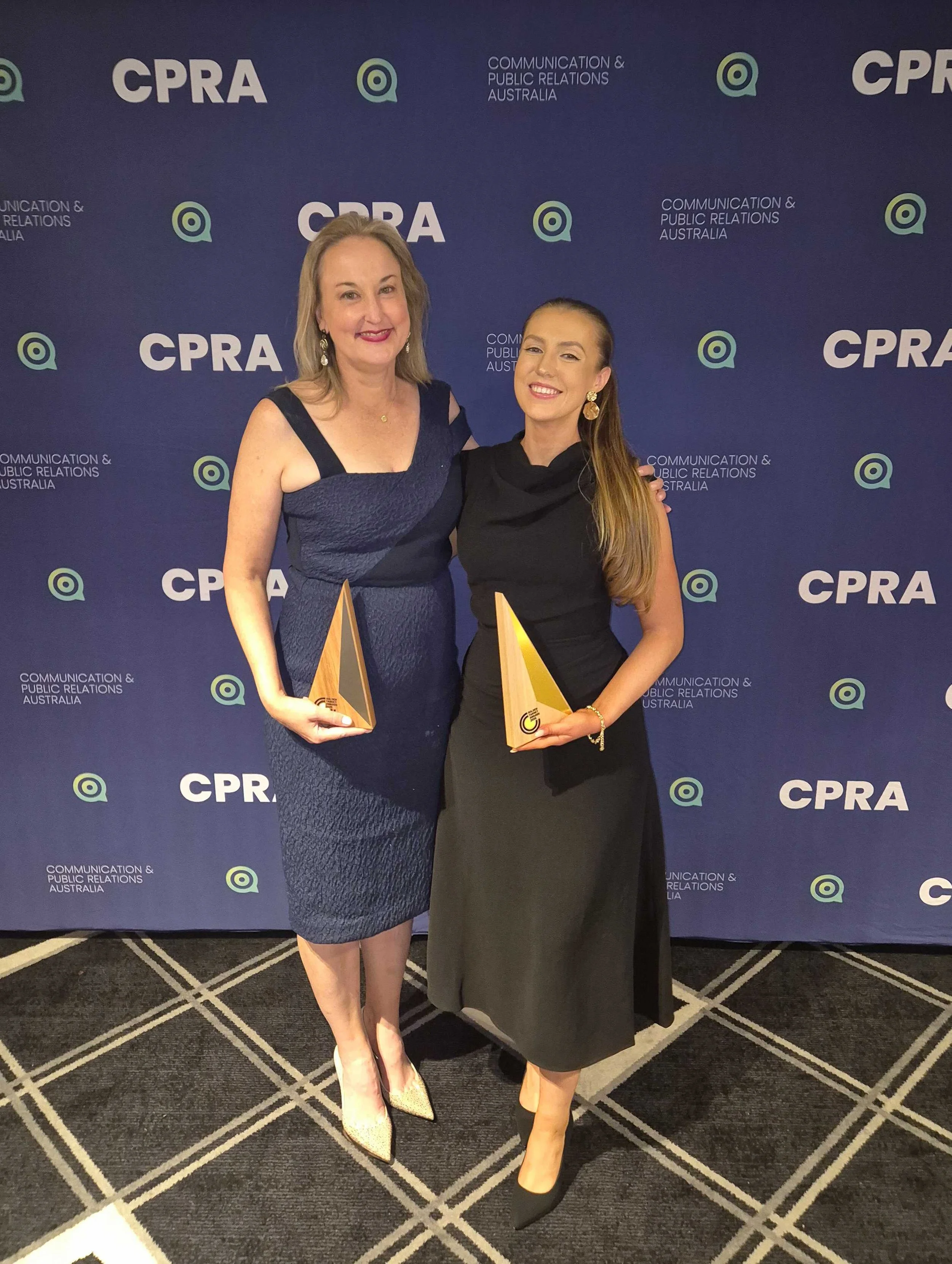 An image of two Cole Lawson/ We Are Brooklyn award recipients in front of the Communication and Public Relations Australia photo wall.