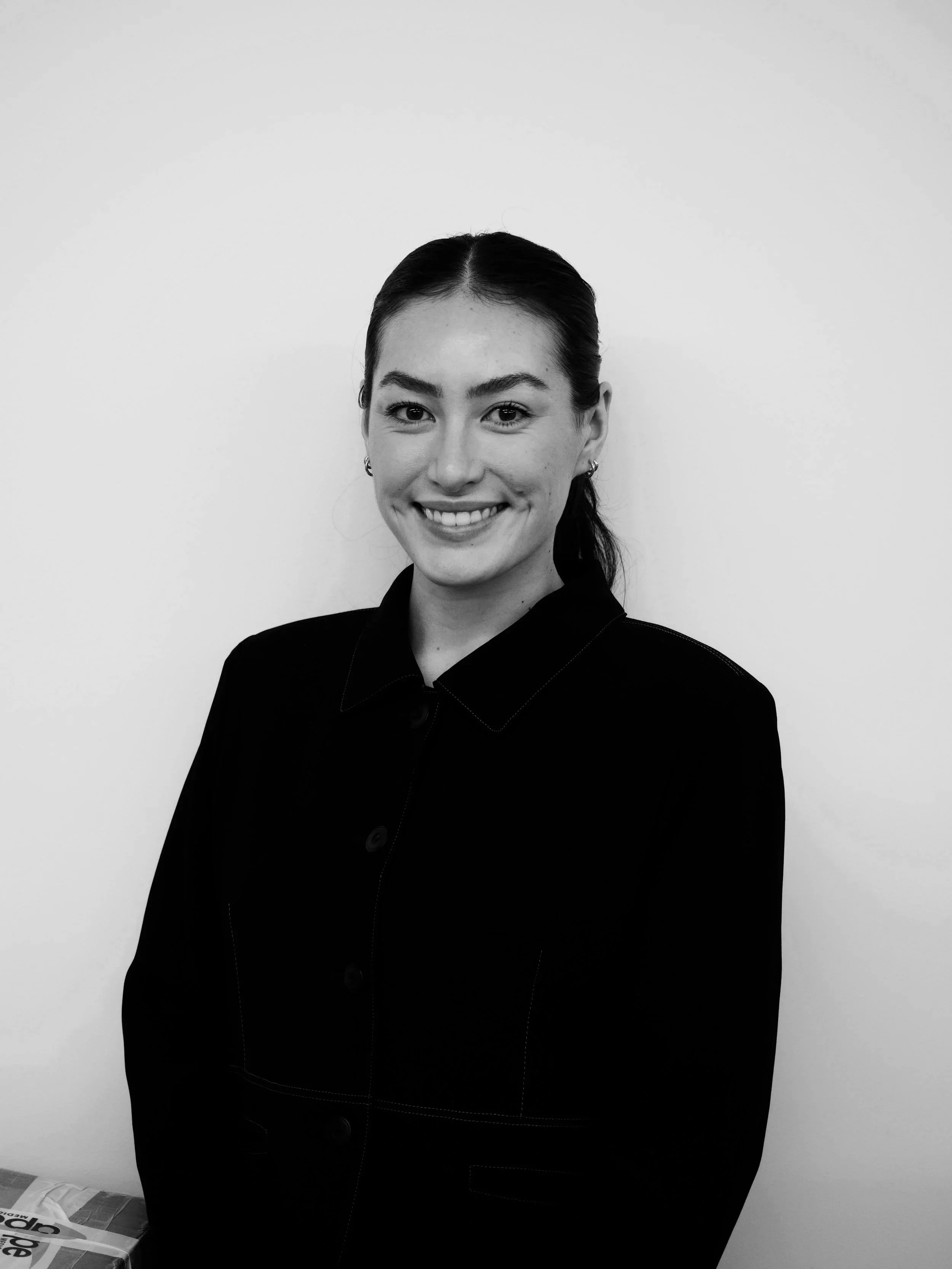 Modern wooden building with large glass window, surrounded by yellow flowers and mountains in the background.