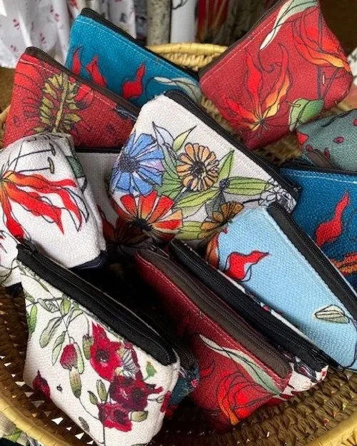 assorted colourful small zipper bags or coin purses with flame lily, zinnia, lucky bean and kigelia zimbabwe flora designs