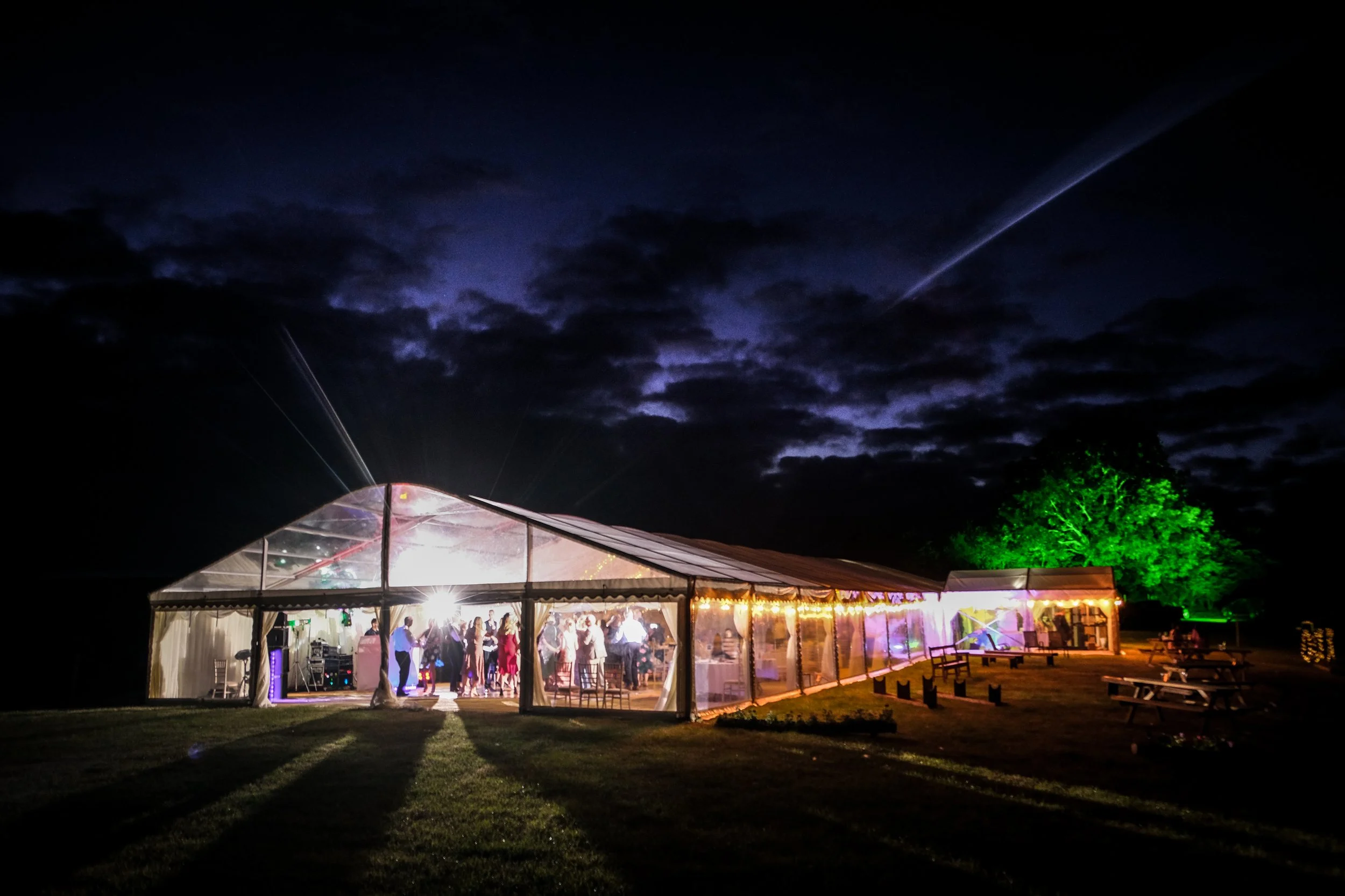 wedding marquee at night with green flood lights and festoon lighting