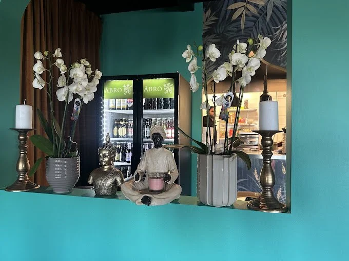 Inredning med statyer och blommor framför en kyldisk i en restaurang.