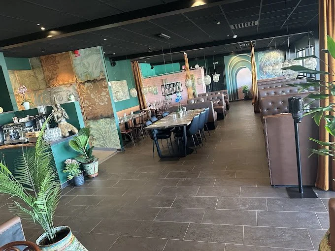 Inredning av en modern restaurang med bruna soffor och bord, växter, och konstnärlig väggdekoration.