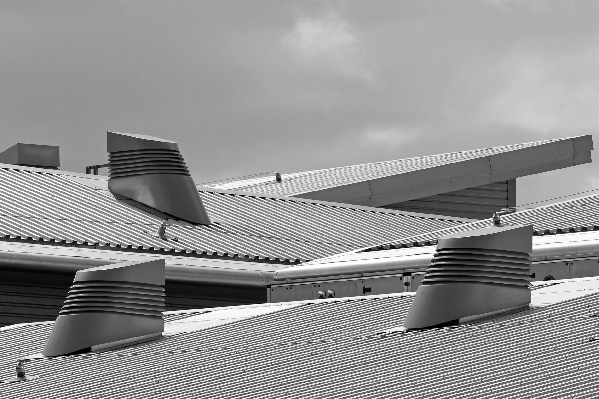 Close-up of metal building roofs with vents and skylights, black and white photo.